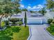 Charming one-story white home featuring a three-car garage, manicured lawn, and mature trees at 1419 Arbor Trl, The Villages, FL 32162