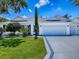 Charming one-story white home featuring a three-car garage and manicured lawn at 1419 Arbor Trl, The Villages, FL 32162