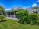 Backyard with an enclosed lanai area, lush landscaping, and a green lawn at 1419 Arbor Trl, The Villages, FL 32162
