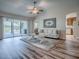 Open living room with hardwood flooring, ceiling fan, sliders to the lanai, and neutral decor at 1419 Arbor Trl, The Villages, FL 32162