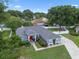 A beautiful home with a well-manicured front lawn, mature trees, long driveway, and a red front door at 14708 Timucua Pl, Clermont, FL 34711