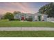 Charming single-story home featuring a red front door, well-manicured lawn, and mature landscaping at 14708 Timucua Pl, Clermont, FL 34711