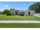 Charming single-story home featuring a red front door, well-manicured lawn, and mature landscaping at 14708 Timucua Pl, Clermont, FL 34711