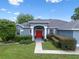 Attractive single-story home with a red front door, columned entrance, and professionally landscaped yard at 14708 Timucua Pl, Clermont, FL 34711