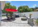 Backyard patio featuring a dining set, umbrellas, a fire pit, and well manicured plantings at 14708 Timucua Pl, Clermont, FL 34711