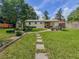 Backyard with green grass and stepping stones leading to a seating area with an umbrella and landscaping at 1537 Ne 22Nd St, Ocala, FL 34470