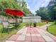 Lush backyard featuring an outdoor dining set under a red umbrella on a decorative brick path leading to a shed at 1537 Ne 22Nd St, Ocala, FL 34470