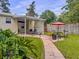 View of backyard that offers a covered patio, brick path, outdoor dining, and a lush lawn bordered by mature trees at 1537 Ne 22Nd St, Ocala, FL 34470