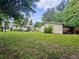 Spacious backyard featuring a lawn and a shed with a covered area for equipment storage, surrounded by lush greenery at 1537 Ne 22Nd St, Ocala, FL 34470
