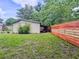 View of backyard featuring storage shed, mature trees, and a newly stained fence - some sections in a vibrant red at 1537 Ne 22Nd St, Ocala, FL 34470