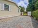 View of the side yard with gravel and a gated entrance to the backyard, showing the home's siding and windows at 1537 Ne 22Nd St, Ocala, FL 34470