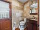A bathroom with tile walls, wood floors, a toilet, and a wood door to the outside at 15733 Tower View Dr, Clermont, FL 34711