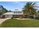 Inviting home featuring a well manicured lawn, mature palm trees, fountain, and a convenient two car garage at 15733 Tower View Dr, Clermont, FL 34711
