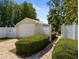 View of the detached garage with white garage door, hedges, and brick path at 15733 Tower View Dr, Clermont, FL 34711