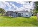 Backyard view showcasing the screened patio and well-maintained landscaping at 15828 Se 98Th Ter, Summerfield, FL 34491