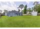 Spacious backyard featuring a screened lanai, lush green lawn, storage shed, and a wood privacy fence at 15828 Se 98Th Ter, Summerfield, FL 34491