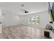 Open-concept living room with wood-look floors, bright windows, and ceiling fan at 15828 Se 98Th Ter, Summerfield, FL 34491