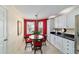 Cozy dining area featuring a round table, white cabinets, and bright red accent wall at 16730 Se 78Th Lillywood Ct, The Villages, FL 32162
