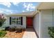 Close-up of home's entrance showcasing the red front door, black shutters, and brick paver walkway at 16730 Se 78Th Lillywood Ct, The Villages, FL 32162
