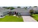 Well-manicured home featuring lush green lawn, mature landscaping, and a brick paver driveway at 16730 Se 78Th Lillywood Ct, The Villages, FL 32162
