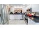 Kitchen with stainless steel appliances, white cabinets, and a view into the living area at 16730 Se 78Th Lillywood Ct, The Villages, FL 32162