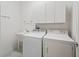 Bright laundry room with a washer, dryer, sink, and overhead storage cabinets at 1762 Meadowlark Ave, The Villages, FL 32162