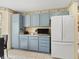 Well-lit kitchen featuring blue cabinets, white appliances, and a clean, efficient design for cooking at 17860 Se 89Th Natchez Ave, The Villages, FL 32162