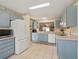 Well-equipped kitchen featuring blue cabinets, white appliances, and an open layout for easy meal preparation at 17860 Se 89Th Natchez Ave, The Villages, FL 32162
