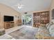 Open living room area with tile flooring, a built-in bookcase, and sliding glass doors to the outdoor patio at 17860 Se 89Th Natchez Ave, The Villages, FL 32162