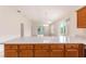 Kitchen view showcases a breakfast bar with wood cabinets and light countertops, overlooking a living area with light floors at 2101 Southern Star Way, The Villages, FL 32162