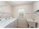Functional laundry room featuring a utility sink, laundry machines and shelving at 2101 Southern Star Way, The Villages, FL 32162
