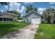 Well-kept home with an attached garage, long driveway, and a front yard filled with flowers and a mature palm tree at 2110 Churchill Downs Cir, Orlando, FL 32825