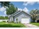 Landscaped front of gray single-story home with an attached garage, flowers, and a white front door at 2110 Churchill Downs Cir, Orlando, FL 32825