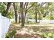 Spacious backyard with green grass, shade trees, a white fence, and sitting areas at 2112 Waitman, Leesburg, FL 34748