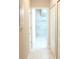 Hallway with white tiled floors and white doors that lead to a bathroom featuring glass shower at 2112 Waitman, Leesburg, FL 34748