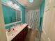 Bathroom with double vanity, shower with curtain, and turquoise walls at 2122 Waseca Ln, Leesburg, FL 34748