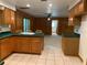 Open kitchen with wood cabinets, bar seating, tile floors, and view of living area at 2530 Shady Ln, Groveland, FL 34736