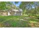 Wide backyard featuring a simple house exterior, lawn, and surrounding trees at 2708 Lorraine Dr, Leesburg, FL 34748