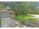 Home exterior featuring a driveway, garage door, and lawn with mature trees, showcasing curb appeal at 2708 Lorraine Dr, Leesburg, FL 34748