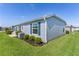 Side view of a single-story home with blue shutters, manicured landscaping, and a green lawn at 3283 Dawn Pl, The Villages, FL 32163
