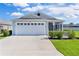 Well-kept single-story home with a two-car garage, a screened-in porch, and lush landscaping at 3283 Dawn Pl, The Villages, FL 32163