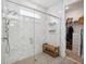 Modern bathroom featuring a glass-enclosed shower with marble tile and a bench, plus access to the walk-in closet at 3304 Canna Lily Pl, Clermont, FL 34711