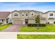 Beautiful two-story home with lush green lawn, a brick driveway, and manicured landscaping at 3304 Canna Lily Pl, Clermont, FL 34711