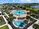 Aerial view of a resort-style community pool, palm trees, lounge chairs, and splash pad on a sunny day at 3304 Canna Lily Pl, Clermont, FL 34711