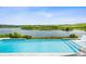 Stunning pool and lake view with a chair in the water for lounging while enjoying the expansive vista at 3304 Canna Lily Pl, Clermont, FL 34711