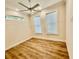 Bright bedroom with wood floors, two windows, ceiling fan, and neutral paint at 3607 Umbrella Tree Ln, Oxford, FL 34484
