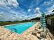 Sparkling community pool with lounge area, umbrellas, and sunny sky at 3607 Umbrella Tree Ln, Oxford, FL 34484