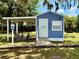 Community golf cart parking area next to a small blue building with bike rack and covered parking at 3607 Umbrella Tree Ln, Oxford, FL 34484