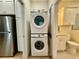 A laundry room with stacked washer and dryer with white cabinets and a stainless steel refrigerator at 3607 Umbrella Tree Ln, Oxford, FL 34484
