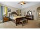 Cozy bedroom with a large bed, wooden furniture, ceiling fan, and neutral color scheme at 4018 Chandler Estates Dr, Apopka, FL 32712